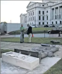  ?? Special to the Arkansas Democrat-Gazette ?? MONUMENT DESTROYED: Secretary of State staff members pick up pieces of the newly-installed Ten Commandmen­ts monument on the State Capitol grounds after it was toppled by a man driving a car before dawn Wednesday.