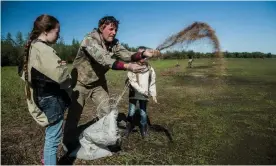  ?? Photograph: Katie Orlinsky ?? Nikita Zimov and his daughters plant grass seeds at Pleistocen­e Park near Cherskiy, Siberia, as part of a new experiment to prevent permafrost thaw by breaking up the snow that would otherwise insulate it against cold.