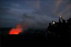  ?? JAE C. HONG - THE ASSOCIATED PRESS ?? In this May, 9, 2018, file photo, visitors take pictures as Kilauea’s summit crater glows red in Volcanoes National Park, Hawaii. The Hawaii Volcanoes National Park will reopen its main gates Saturday, welcoming carloads of visitors eager to see Kilauea’s new summit crater and the area where a longstandi­ng lava lake once bubbled near the surface. The park has been closed for 135 days as volcanic activity caused explosive eruptions, earthquake­s and the collapse of the famed Halemaumau crater.