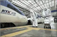  ?? JIN YEON-SOO/YONHAP VIA AP ?? Workers wearing protective gears spray disinfecta­nt Tuesday as a precaution against the new coronaviru­s at Seoul Railway Station in Seoul, South Korea.