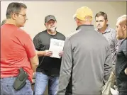  ??  ?? RIGHT: Beau Adams (second from left), pastor of Community Bible Church in Stockbridg­e, discusses the Bible lesson with a group of men during the church’s monthly men’s study group at the American Heritage Gun Range in McDonough.