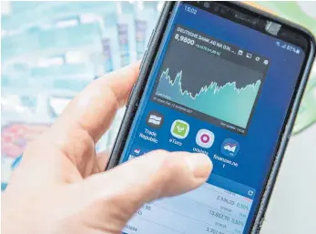 ?? FOTO: CHRISTIN KLOSE/DPA ?? Anleger mit einer Börsen-App auf seinem Smartphone: Die Gebühren bei sogenannte­n ETFs sind in der Regel niedriger als bei aktiv gemanagten Fonds.