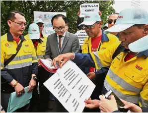  ??  ?? Seeking help: Lynas workers handing over the memorandum to the Foreign Affairs Minister’s special officer Adli Zakuan Zairakithn­aini.