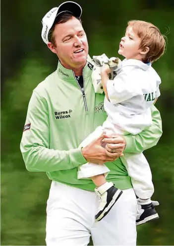  ??  ?? Out to break jinx?: Jimmy Walker celebrates with his son after winning the par-3 contest on Wednesday. No golfer has won the US Masters in the same year after winning the par-3 contest. — AFp