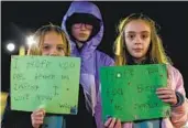  ?? JOHN C. CLARK AP ?? Children hold supportive signs at a candleligh­t vigil on Jan. 9 for the teacher who was shot.