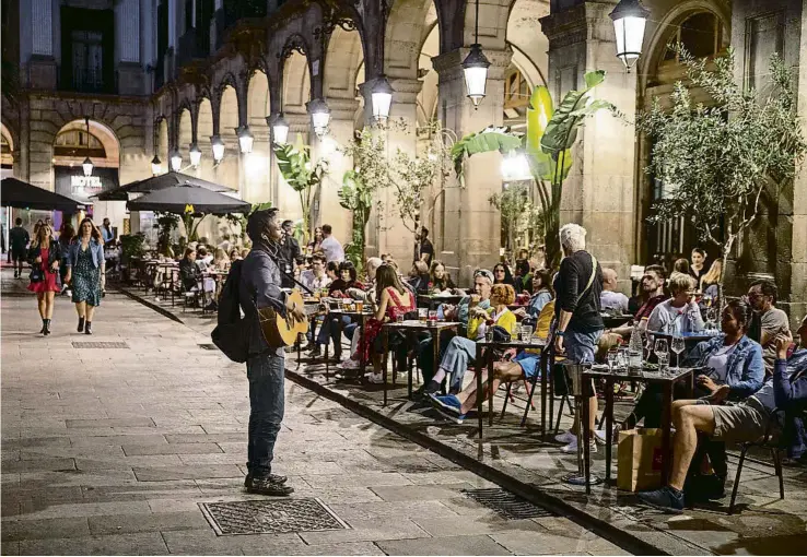  ?? MANÉ ESPINOSA ?? Un músic de carrer toca la guitarra davant els turistes asseguts a les terrasses dels bars de la plaça Reial de Barcelona