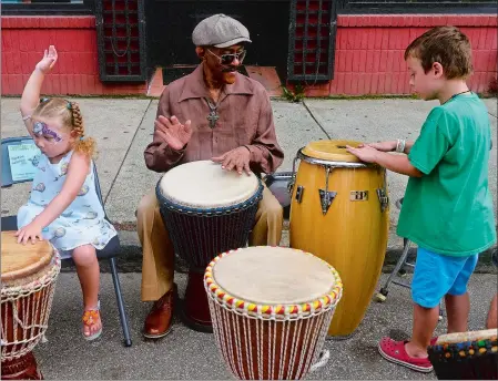  ?? SARAH GORDON/THE DAY ?? Lillian Guess, 3, of New London, left, plays the drums Sunday with Apache, who did not give his last name, of New York, and Oscar Stallard, 5, of New London, on Bank Street during the final day of Sailfest in New London.