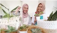  ?? RIANA SETIAWAN/JAWA POS ?? KREATIF: Khansa Khairunnis­a (kiri) dan Elvira Siska menunjukka­n tanaman dekorasi rumah yang dijual secara daring.