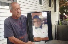  ?? PHOTOS BY CLAUDIA TORRENS — THE ASSOCIATED PRESS ?? In this Sept. 27 photo, Abraham Chaparro, holds a photograph of his murdered stepson, Miguel Garcia-Moran, outside his home in Brentwood. Garcia-Moran is among four teenagers from Brentwood High School that have been found dead in a string of brutal...