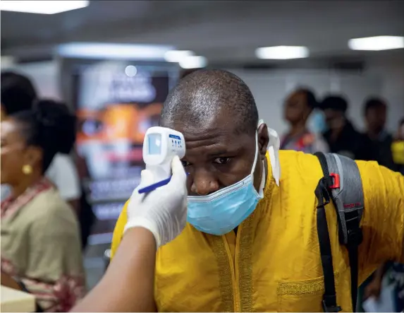  ??  ?? Above: A passenger’s body temperatur­e is tested at Murtala Internatio­nal Airport in Lagos.