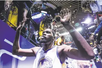  ?? Gabrielle Lurie / The Chronicle ?? Durant high-fives fans in the tunnel at Oracle Arena after the Warriors defeated the Cavaliers.