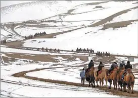  ?? ZHANG XIAOLIANG / FOR CHINA DAILY ?? Tourists ride camels at the Mingsha Mountain Crescent Spring in Dunhuang, Gansu province, on Feb 19.