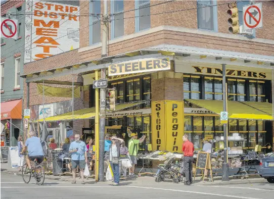  ?? PHOTOS: JIM JUDKIS/THE WASHINGTON POST ?? Shoppers stroll by Yinzers sportswear shop in the heart of Pittsburgh’s Strip District, which has a profusion of small ethnic grocery stores.