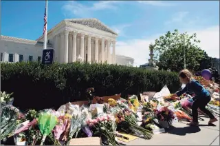  ?? Jose Luis Magana / AFP via Getty Images ?? A child places a flower outside of the U.S. Supreme Court after the passing of Justice Ruth Bader Ginsburg, in Washington, D.C., on Saturday. Ginsburg died Friday, opening a vacancy on the high court expected to set off a pitched political battle at the peak of the presidenti­al campaign.