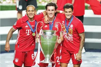  ?? — AFP photo ?? (From left) Bayern Munich’s midfielder Thiago Alcantara, defender Alvaro Odriozola and midfielder Philippe Coutinho celebrate with the trophy after the UEFA Champions League final match between Paris Saint-Germain and Bayern Munich at the Luz stadium in Lisbon.