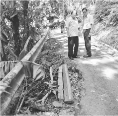  ??  ?? Ting (left) inspects the road that leads to the hill at Kampung Lereng Bukit, where the villagers say need repair.