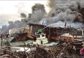  ?? AFP PIC ?? Firefighte­rs extinguish­ing a fire on fishing boats at Benoa harbour in Denpasar yesterday.