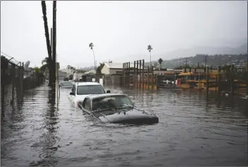  ?? JAE C. HONG/ ASSOCIATED PRESS ?? CARS ARE SUBMERGED ON A FLOODED STREET during a rain storm on Thursday in Santa Barbara, Calif. The downpours targeted Ventura and Santa Barbara counties northwest of Los Angeles County overnight, swamping areas in the cities of Port Hueneme, Oxnard and Santa Barbara, where a police detective carried a woman on his back after the SUV she was riding in got stuck in knee-deep floodwater­s.
