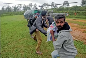  ?? Reuters ?? Flood victims unload relief material from an IAF helicopter at Nelliyampa­thy Village. —