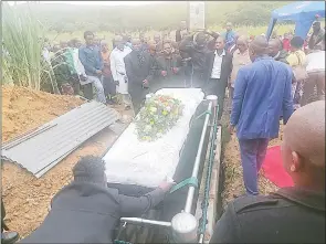  ?? (Pics: Sibusiso Shange) ?? A section of the family members look on as a member of SNAT Burial Scheme adjust the blanket before the casket of the late Sandile Macanda Nkambule was lowered into the grave.