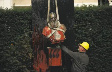  ?? Francisco Seco / Associated Press ?? A bust of King Leopold II is removed in Ghent, Belgium. His search for wealth killed millions in Congo.