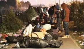  ?? PHILIPPE HUGUEN/AFP ?? Migrants who slept outside an aid station queue to be assigned one of the processing centres across France, near the ‘Jungle’ camp yesterday.