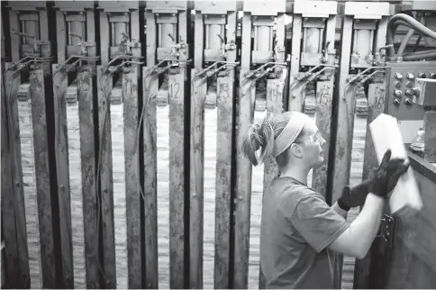  ?? — WP-Bloombeg photo ?? A worker places maple lumber panels used to manufactur­e bowling pins into machinery at the QubicaAMF Bowling Worldwide facility in Lowville, New York.