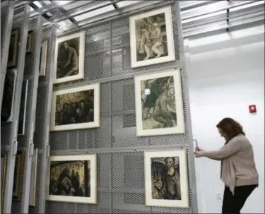  ?? CAROLYN KASTER — THE ASSOCIATED PRESS ?? Laura Seylar, registrar of Collection­s Management, slides open a section of the art rack at the U.S. Holocaust Memorial Museum’s David and Fela Shapell Family Collection­s, Conservati­on and Research Center in Bowie, Md., Monday. The art racks holds...