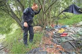  ??  ?? Los Angeles police officer Rusty Redican looks over a homeless encampment in the hills of Pacific Palisades that was cleared out.