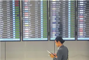  ??  ?? A woman stands at a display of flight informatio­n at Suvarnabhu­mi airport. South Korean airlines have suspended more flights to Thailand.