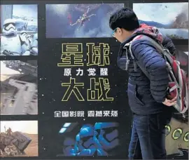  ?? How Hwee Young EPA ?? A PASSERBY LOOKS at a poster with scenes from “Stars Wars: The Force Awakens” outside a movie theater in Beijing this month.