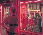  ?? JASPER JUINEN THE NEW YORK TIMES ?? A sex worker dances in front of a window in the red-light district as tourists pass by in Amsterdam.