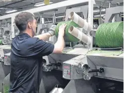  ??  ?? A Low & Bonar technician checks a yarn spool. The firm’s share price fell sharply following the boardroom changes.