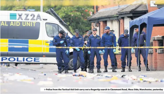  ??  ?? &gt; Police from the Tactical Aid Unit carry out a fingertip search in Claremont Road, Moss Side, Manchester, yesterday