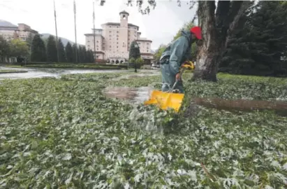  ?? Photos by Jerilee Bennett, The Gazette ?? Broadmoor Hotel employee Carlton Burton shovels leaves and hail after a storm Monday damaged trees, vehicles and buildings in the Colorado Springs area.