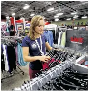  ??  ?? Olympic pentathlon hopeful Isabella Isaksen arranges clothing for sale inside Dick’s Sporting Goods, where she works when not training at the Olympic Training Center.