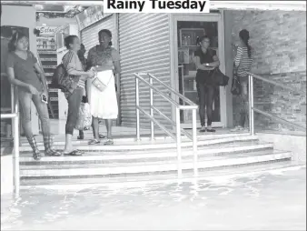  ??  ?? Waiting out the rain at Sharon’s Mall yesterday on King St as floodwater lapped at the stairs