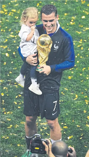  ??  ?? France forward Antoine Griezmann celebrates with his daughter Mia and the Fifa World Cup trophy.
