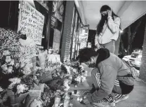  ?? Jeenah Moon / New York Times ?? Jeffrey Riso and Cindy Callejas add candles to a makeshift memorial outside Young’s Asian Massage in Acworth, Ga., in honor of the victims of the deadly Atlanta-area shootings.