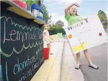  ??  ?? In this July 2011 file photo, Keely Stockham, 10, at right, attempts to flag down drivers to try her lemonade.