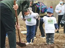  ?? LI HE / XINHUA ?? Children and their parents plant trees in Beijing on March 22.