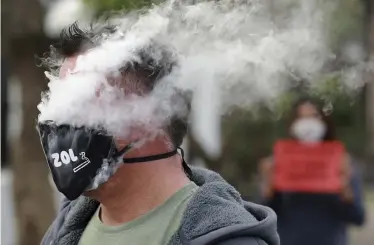  ?? Nardus Engelbrech­t, The Associated Press ?? A protester smokes through his coronaviru­s mask at a demonstrat­ion against South Africa’s tobacco ban Thursday outside parliament in Cape Town.