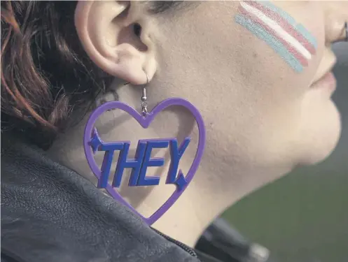  ?? ?? A trans rights activist wears an earring featuring a ‘they’ pronoun symbol