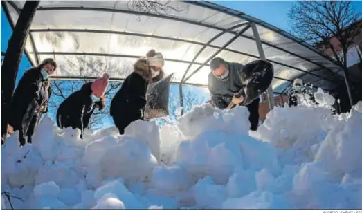  ?? RODRIGO JIMÉNEZ / EFE ?? Personal de limpieza, junto a madres y padres, trabajan en labores de retirada de hielo y nieve ayer en un colegio madrileño.