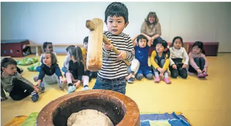  ?? FOTO: A.BRETZ ?? Die Reismasse wird so lange mit Schlägen bearbeitet, bis daraus ein Teig entstanden ist. Auch Yuma, vier Jahre alt, durfte den Hammer schwingen.