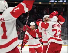  ?? JOHN FROSCHAUER — AP PHOTO ?? Detroit Red Wings defenseman Ben Chiarot, second from right, is hugged by left wing Lucas Raymondas the team celebrates his overtime score against the Seattle Kraken to win an NHL hockey game, Monday, Feb. 19, 2024, in Seattle.