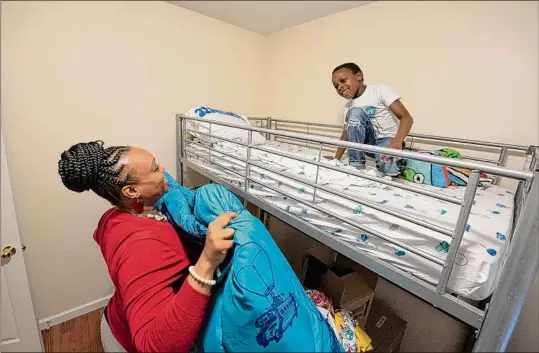  ?? Photos by Lori Van Buren / Times Union ?? Alexandria Carver-Noi helps her 7-yr-old son, Kaiden Noi, make his bed in their new home.