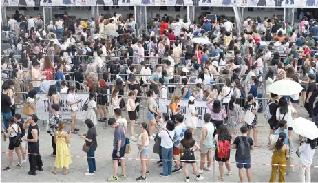  ?? — AFP photo ?? Fans of US singer Taylor Swift, also known as Swifties, line up to buy merchandis­e before the pop star’s Eras Tour concert at the National Stadium in Singapore.