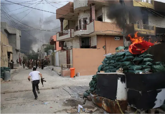  ?? (Goran Tomasevic/Reuters) ?? A KURDISH GUNMAN runs across a street in Tuz Khurmato, Iraq during clashes with a Shiite militia in 2016.