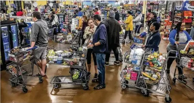  ?? JOHN SPINK / JSPINK@AJC.COM ?? Shoppers line up at the Kroger Marketplac­e at 800 Glenwood Ave. SE in Atlanta on Friday. Greg White, an Atlanta-based supply-chain expert, said shelves are being replenishe­d and the grocery distributi­on system in the U.S. will quickly recover.